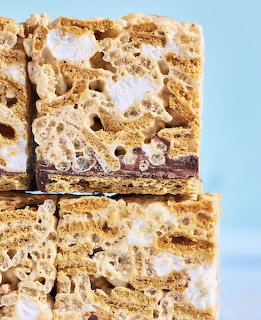 Close-up of stacked rice crispy marshmallow treat bars with chocolate filling on blue background