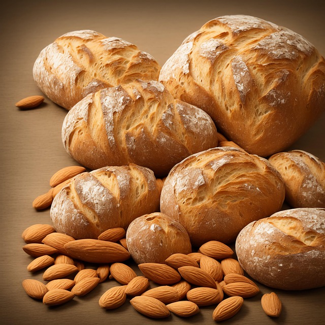 Golden artisan breads with crusty texture arranged with almonds on wooden surface