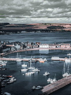 Boats moored in Stonehaven Harbour beside the waterfront under cloudy skies