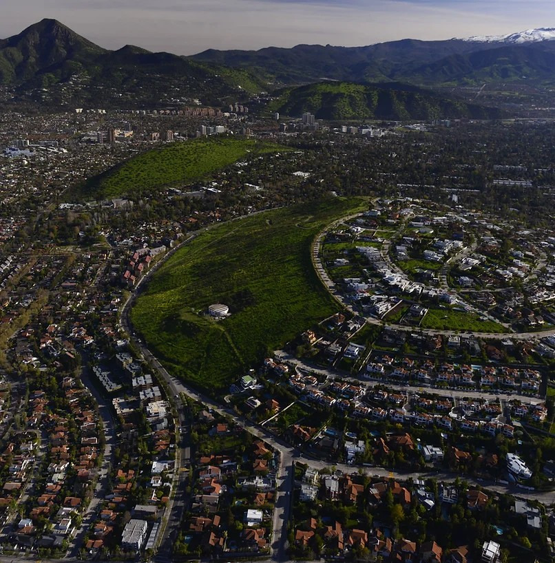 Aerial view of Santiago neighborhood with green hills and mountains behind