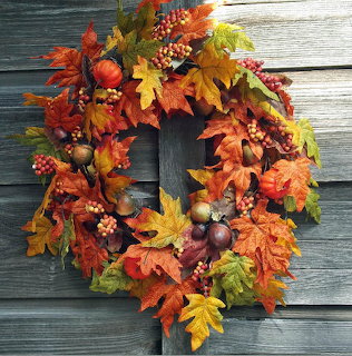 Autumn wreath of fall leaves, berries, and acorns on a gray wooden wall