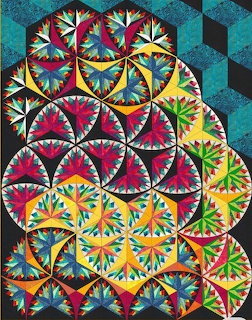 Colorful quilt with circular compass star patterns in pink, blue, yellow, and green on dark background