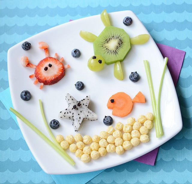 Plate with sea animals made from fruit and cereal, including a kiwi turtle, strawberry crab, and orange fish