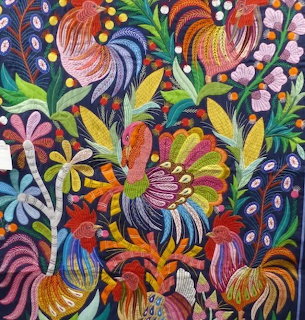 Colorful applique textile showing stylized birds, flowers, and leaves on a dark background