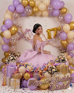 Woman in pink dress sitting with gold number 17 balloon under purple and gold balloon arch at birthday celebration