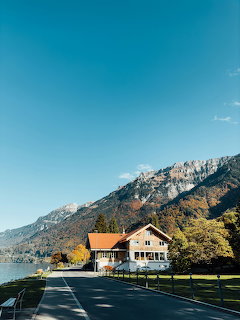 Swiss chalet-style house beside an alpine lake with mountains and clear blue sky on an autumn day