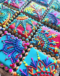 Close-up of elaborately decorated Christmas cookies with colorful icing swirls, patterns, and candy pearl embellishments