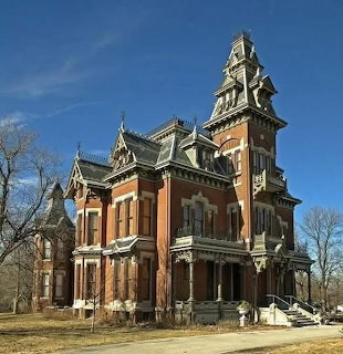 Historic Victorian mansion with central tower and red brick facade under blue sky