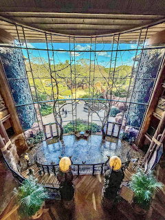 Overhead view of Animal Kingdom Lodge lobby with large window, circular balcony, and lush greenery outside