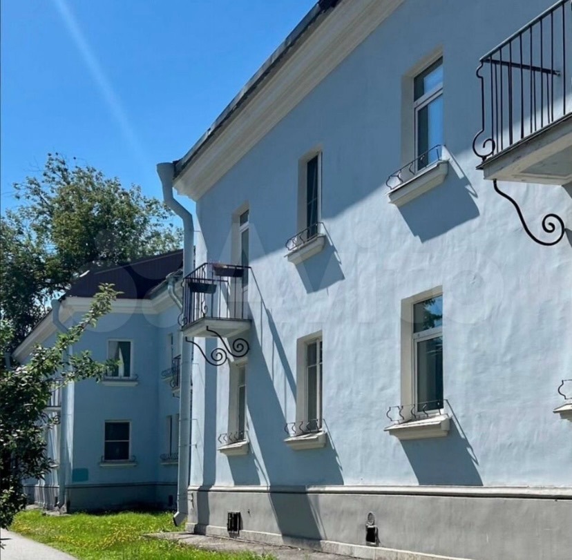White historic building with iron balconies and green shutters on sunny day