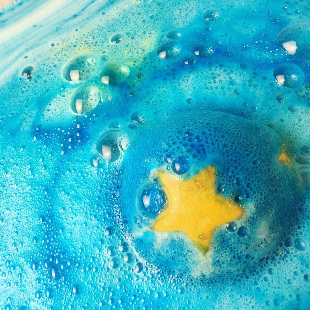 Blue bath bomb fizzing in water with yellow star and bubbles creating turquoise swirls