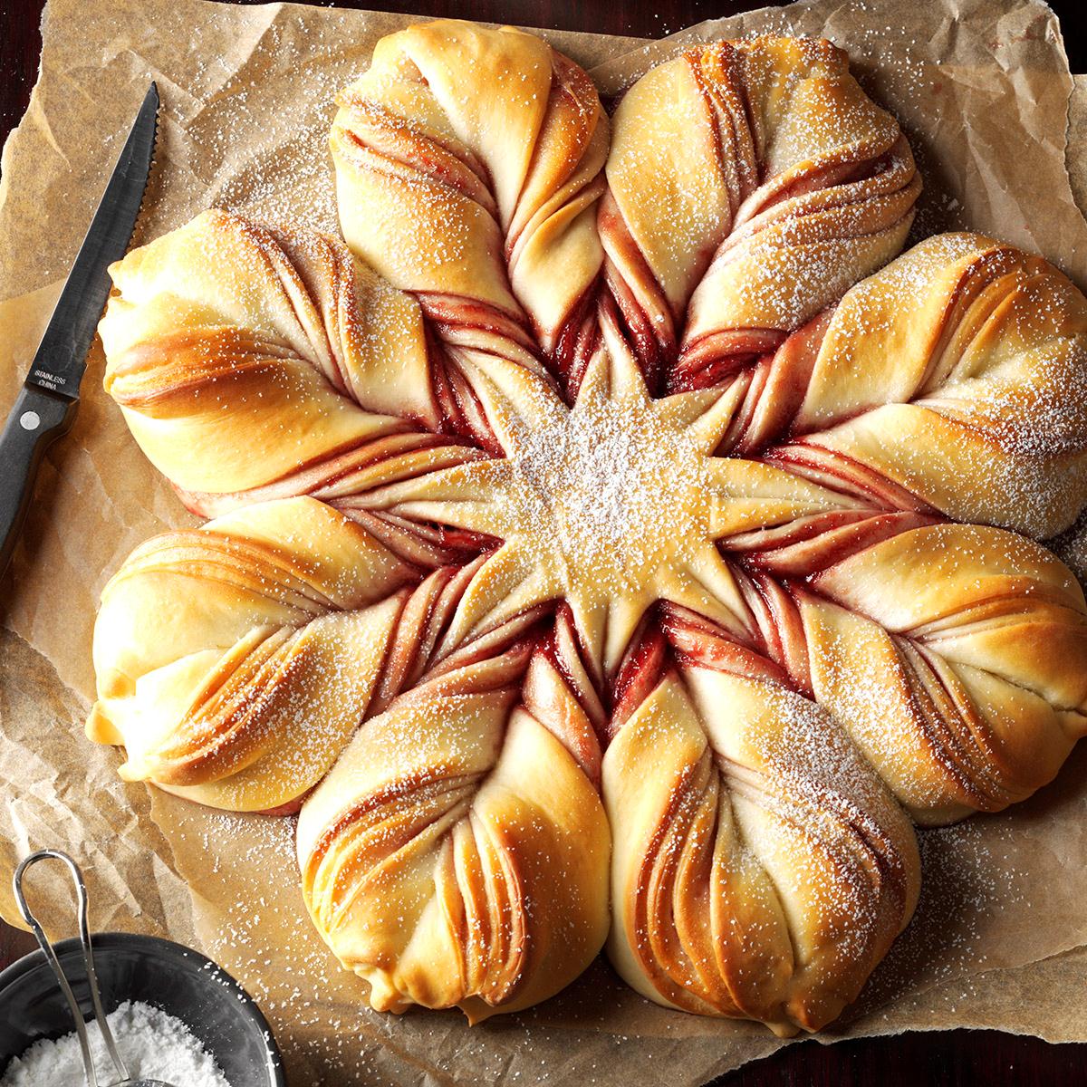 Star-shaped bread with twisted golden petals dusted with sugar on parchment