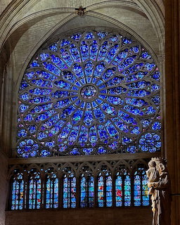Large circular blue stained glass rose window in Notre Dame Cathedral with intricate Gothic tracery and stone arch framing