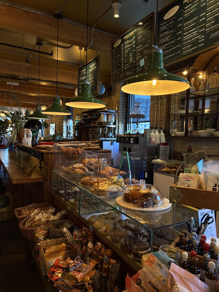 Rustic cafe interior with glass pastry display case, green hanging lights, and chalkboard menu