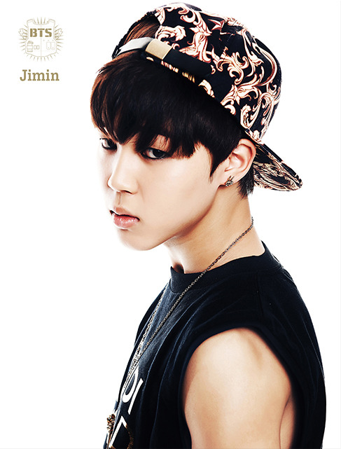 Side-profile portrait of Jimin wearing a patterned cap and black sleeveless shirt