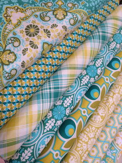 Layers of patterned fabrics with paisley, geometric, plaid and floral designs in blue, yellow, pink and teal colors