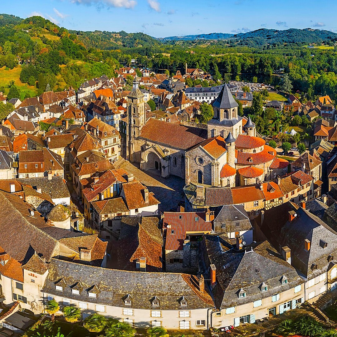 Overhead view of medieval French village with red roofs, church tower, and green hills