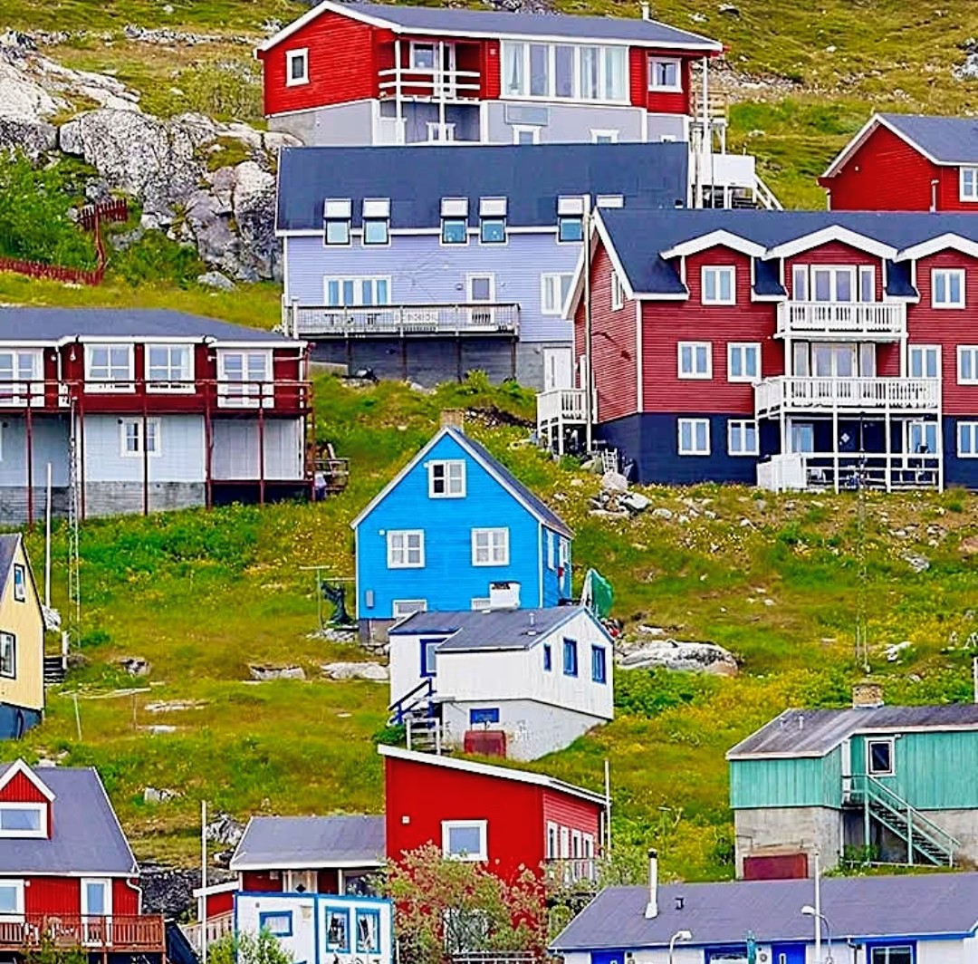 Colorful wooden houses on a green hillside in a coastal fishing village