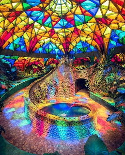 Interior with vibrant stained glass ceiling casting colorful light on reflective floor with circular design