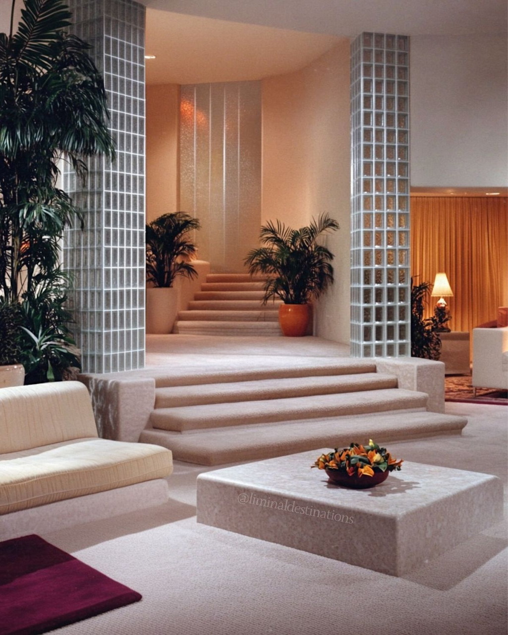 White 1980s living room with glass block walls, plush sofas and mirrored decor