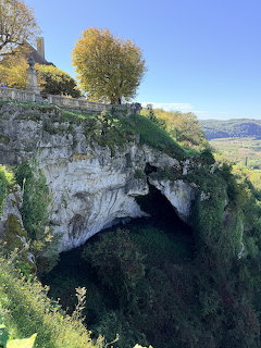 Historic cave dwellings built into a limestone cliff face with trees and valley views in Belves, France