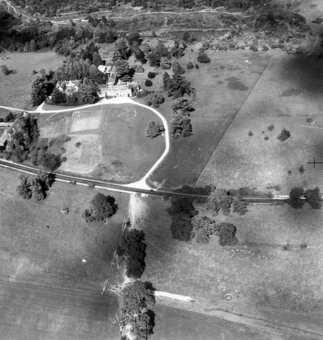 Black and white aerial photo of a country estate with curved driveway and open fields