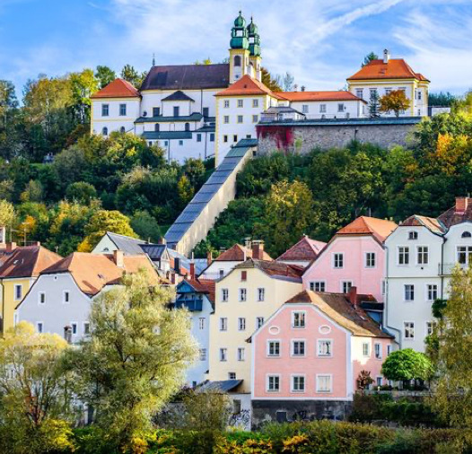 Colorful houses in a hillside town with a white church and green tower on the hiltop connected by covered stairs