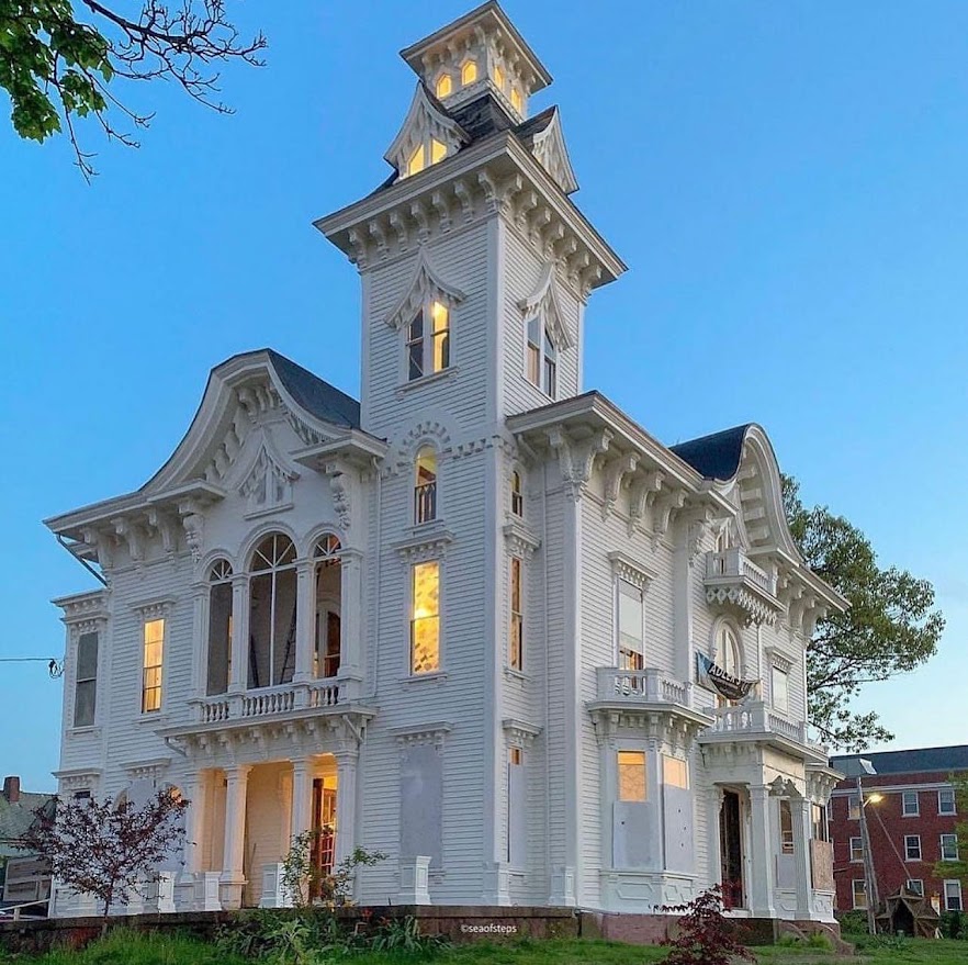 White Victorian house with tall tower and ornate architectural details at twilight