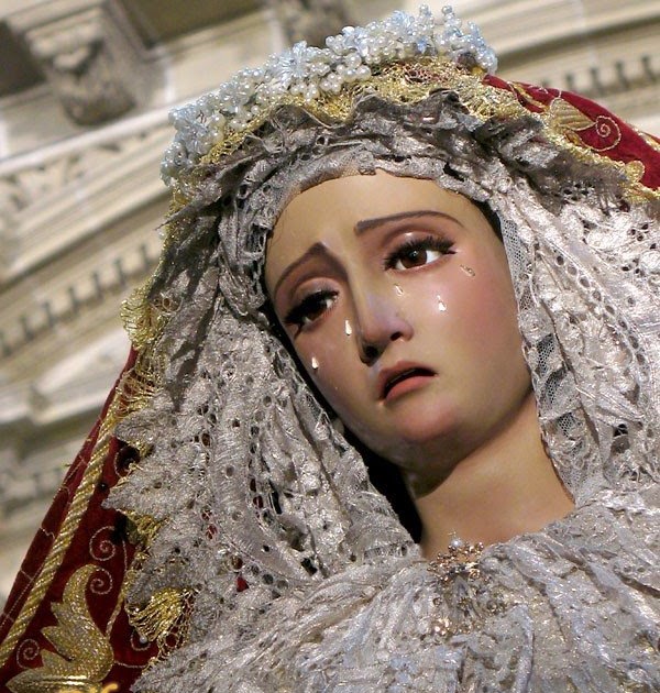 Weping Virgin Mary statue with lace veil, silver crown, and red mantle in a church