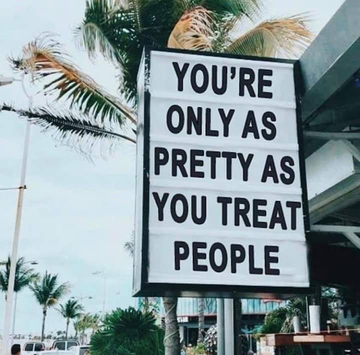 Black and white quote sign outdoors with palm trees in the background