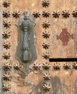Antique brass door knocker on rustic wooden door with metal star decorations
