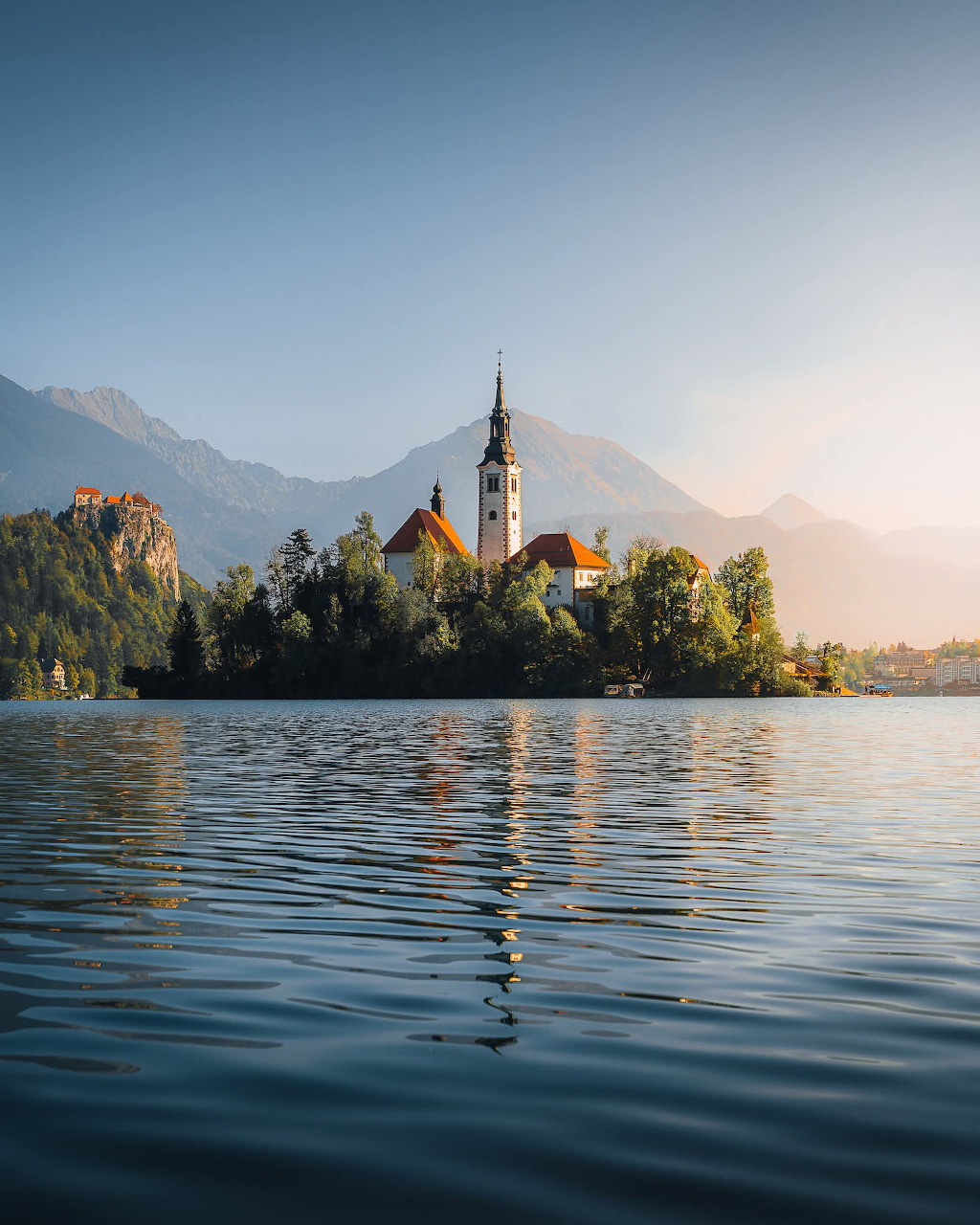 Lake Bled island with church and bell tower reflected in calm water, mountains in background, Slovenia