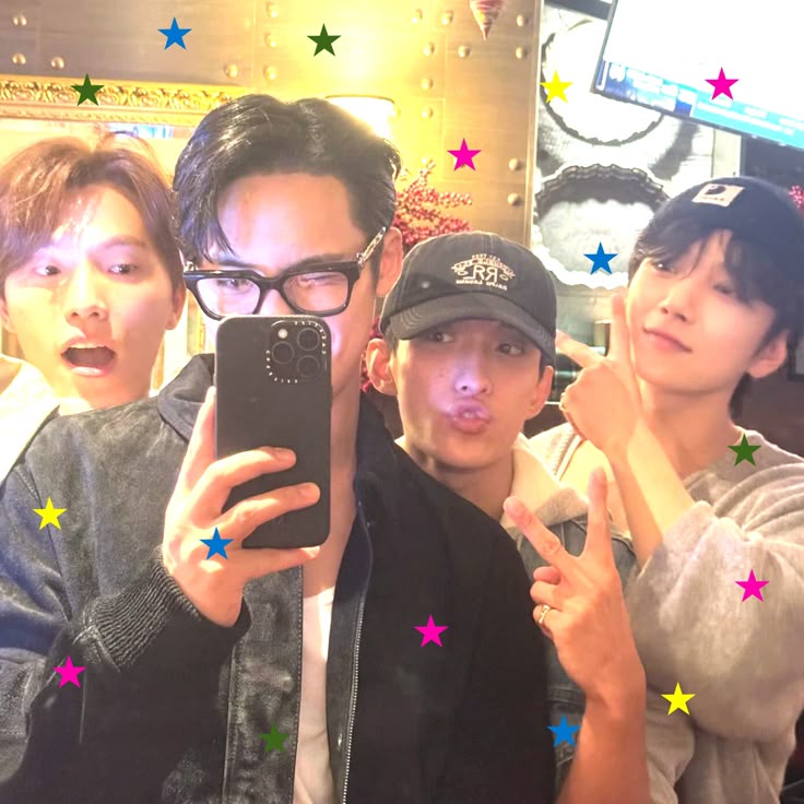 Four young men taking a mirror selfie indoors with colorful star overlays