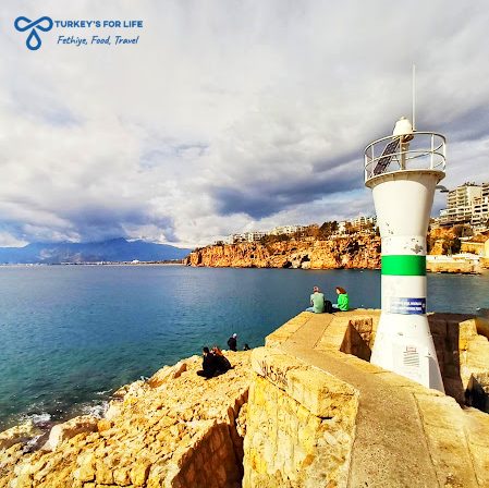 White lighthouse at Antalya old harbour with boats and turquoise sea