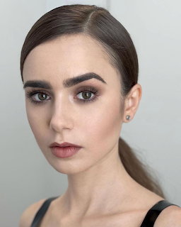 Close-up portrait of Lily Collins with pulled-back hair and smoky eye makeup