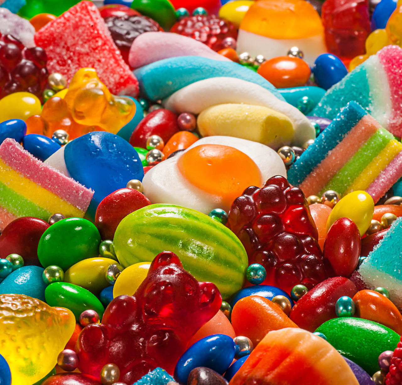 Colorful assortment of various candies including gummy bears, jelly beans, lollipops, and sugar-coated sweets