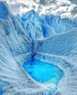 Deep blue ice crevasse with turquoise meltwater pool in Perito Moreno Glacier, Argentina