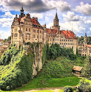 Sigmaringen Castle on cliff with towers and Gothic architecture surrounded by green landscape and dramatic clouds