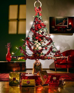 Decorated Christmas tree with presents and red furniture in warm-lit living room