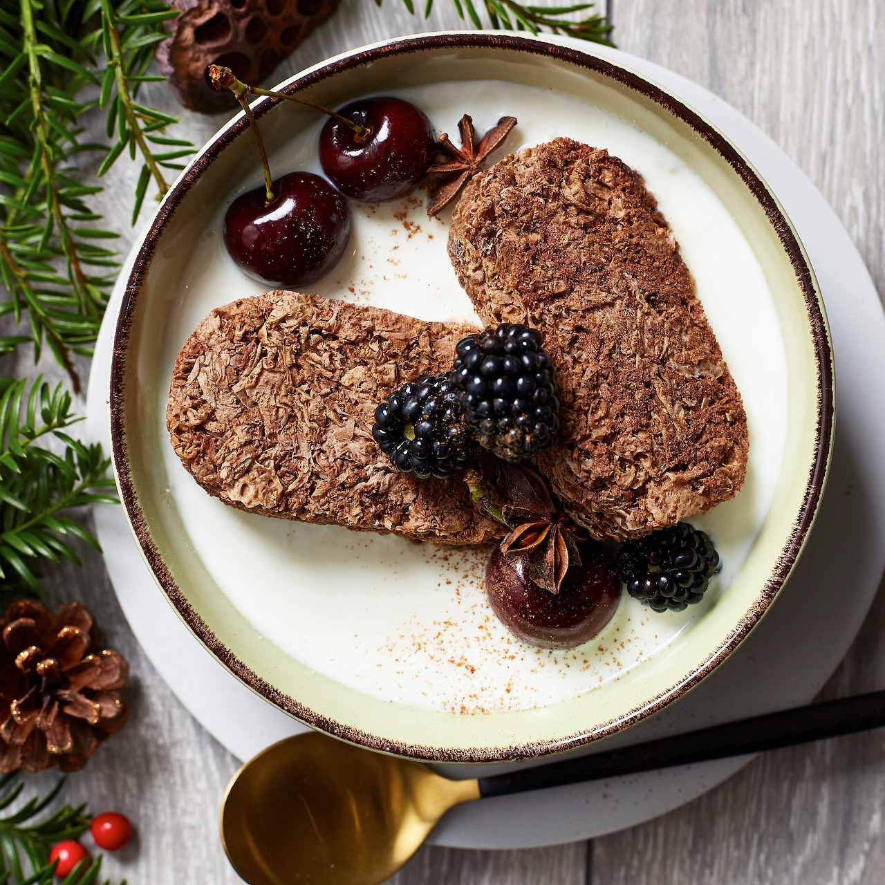 Chocolate pancakes with blackberries and cherries on white plate with rosemary garnish