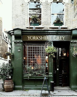 Dark green Yorkshire Grey storefront beneath white brick upper walls