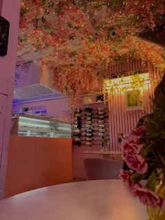 Pink cafe interior with white table, flower ceiling decor, and warm lighting