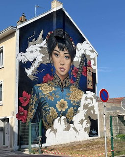 Colorful mural of Asian woman in traditional dress with white cranes painted on building wall