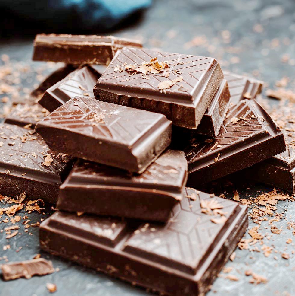 Stack of broken dark chocolate bars with cocoa shavings scattered around