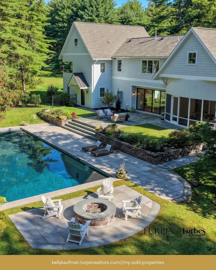 Aerial view of white house with swimming pool and patio in landscaped yard