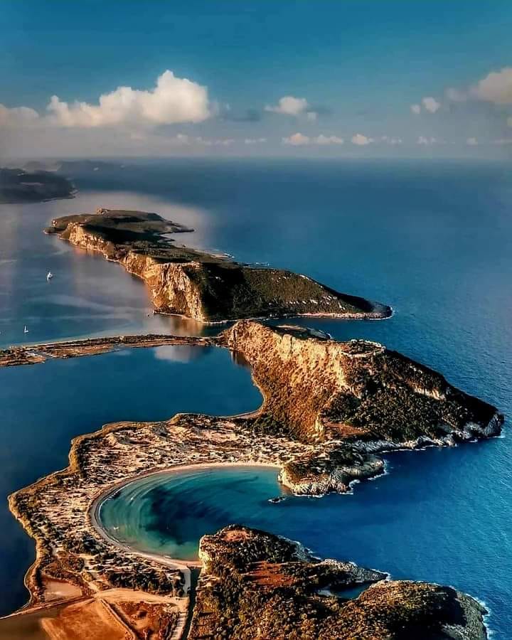 Aerial view of curved beach bay with turquoise water and sandy shores in Greece