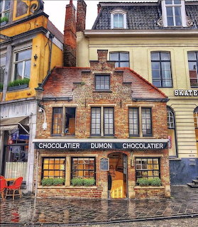 Old brick chocolaterie building with large windows and worn exterior on cobblestone street