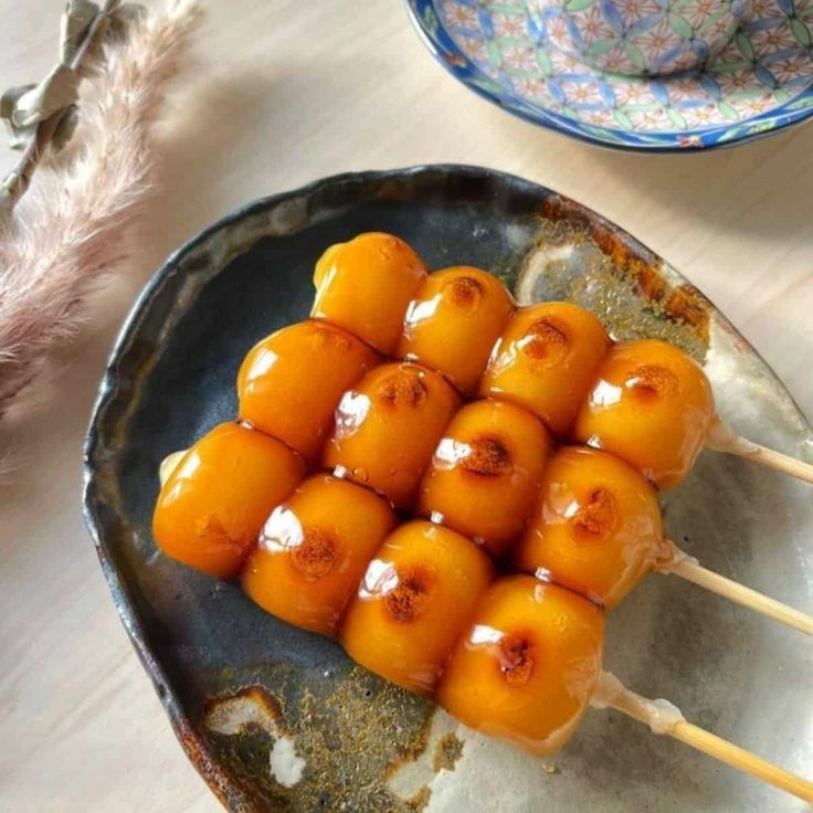 Close-up of two skewers of glazed dango on a dark ceramic plate