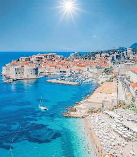 Aerial view of Dubrovnik old town with orange rooftops along the turquoise Adriatic Sea on a sunny day