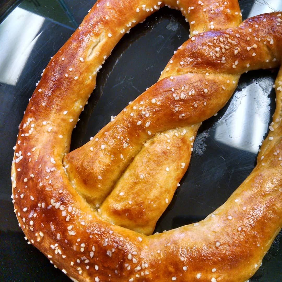 Close-up of a golden soft pretzel with coarse salt on dark background